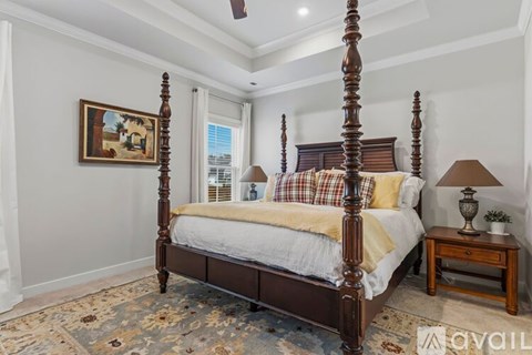 A bedroom with a large bed and a small table with a lamp on it.