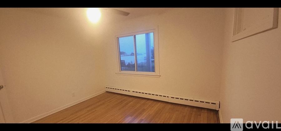 A room with wooden floors and a window showing a view of a building outside.