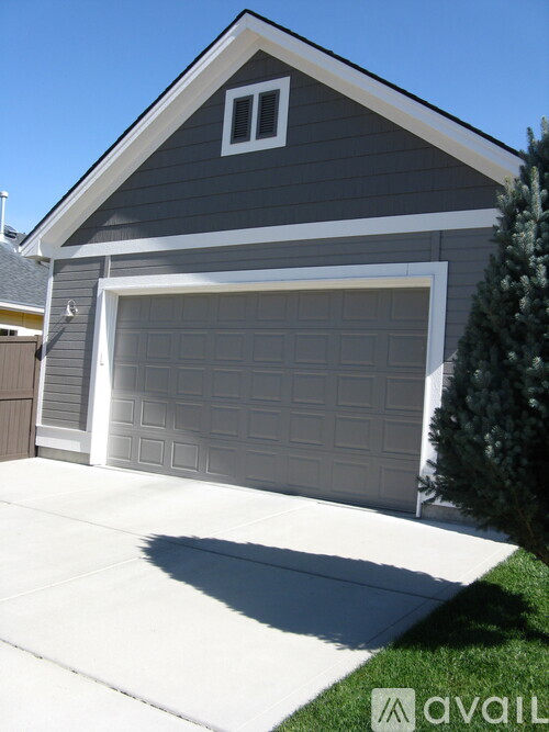 A house with a grey garage door and a white window on the roof.