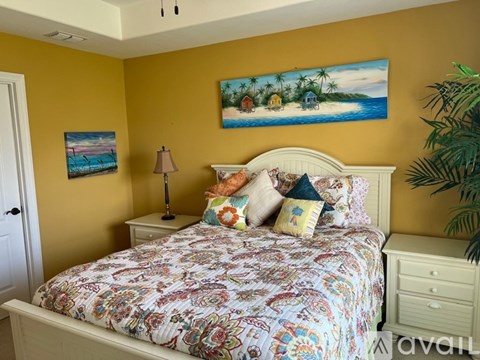 A bedroom with a bed, nightstand, lamp, and two pictures on the wall.