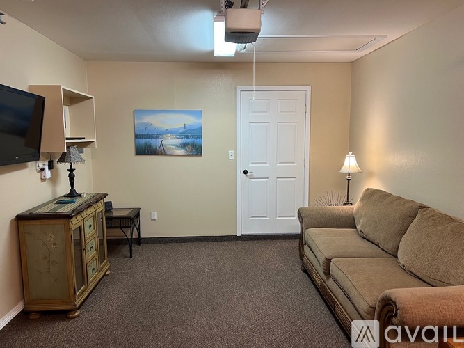 A living room with a couch, a cabinet, a television, and a painting on the wall.