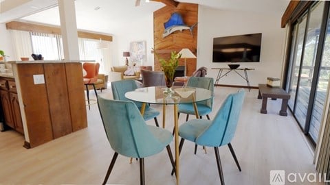 A dining room with a table set for four and a television mounted on the wall.