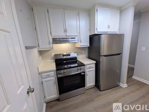 A kitchen with white cabinets and a stainless steel refrigerator.
