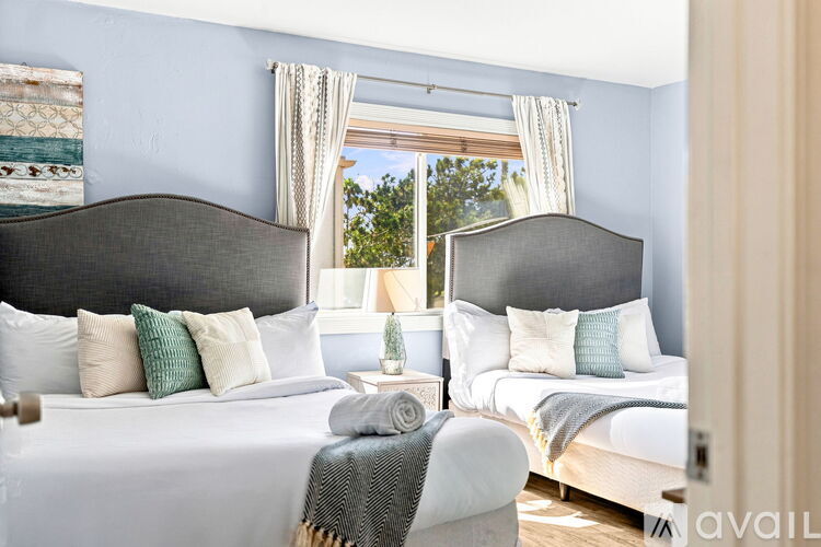 A bedroom with two beds and a window with curtains.