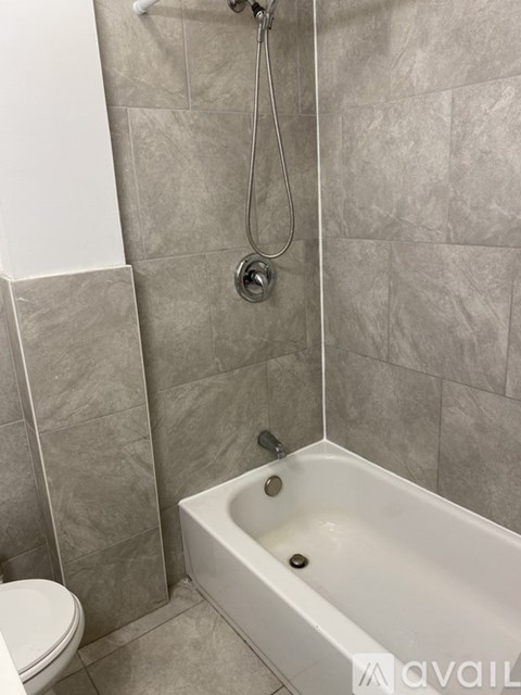 A bathroom with a white tub and grey tiles.