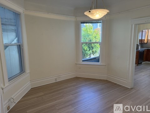 A room with wooden floors and a window with a view of trees.