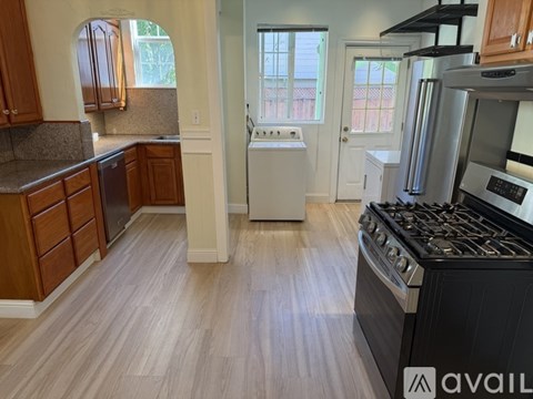 A kitchen with a black stove top oven and wooden floors.