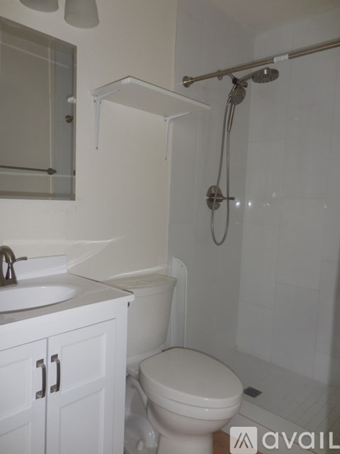 A white toilet in a bathroom with a sink and a shower.