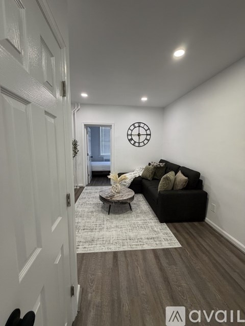A living room with a black couch and a round mirror on the wall.