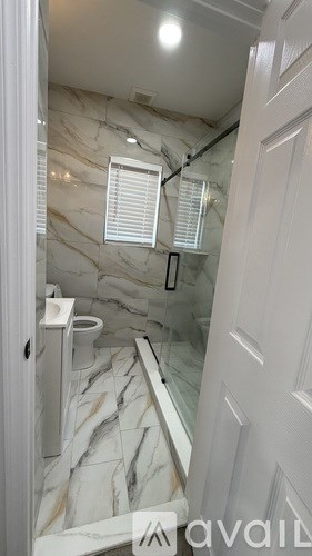 A bathroom with marble tiles and a white door.