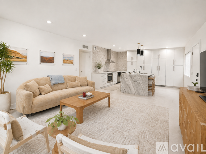 A living room with a couch, coffee table, and a kitchen area in the background.