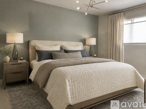 A bedroom with a large bed, two lamps, and a nightstand.