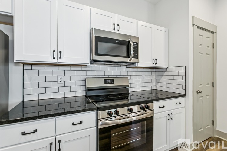 A kitchen with white cabinets and a black and white tiled backsplash.