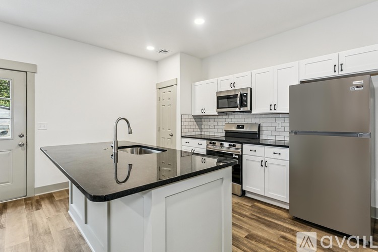 A kitchen with white cabinets and a black countertop.