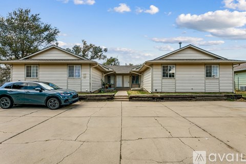 A blue car is parked in front of a two-story house.