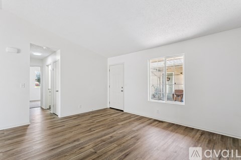 A spacious room with wooden flooring and white walls.