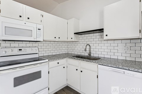 A kitchen with white cabinets and appliances.