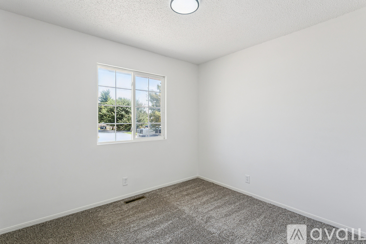 A room with a window showing a view of trees and houses outside.