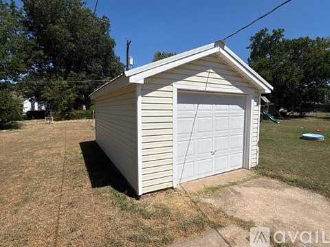 A small white garage with a side door is situated in a grassy area.