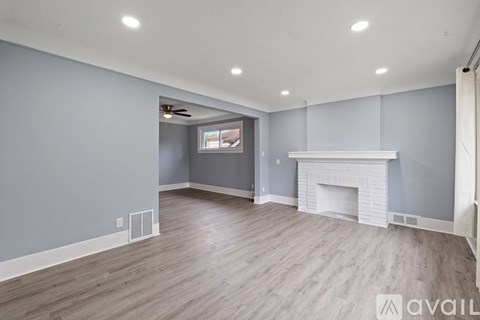 A spacious living room with a fireplace and a ceiling fan.