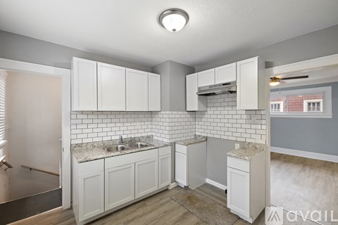 A kitchen with white cabinets and a tiled backsplash.