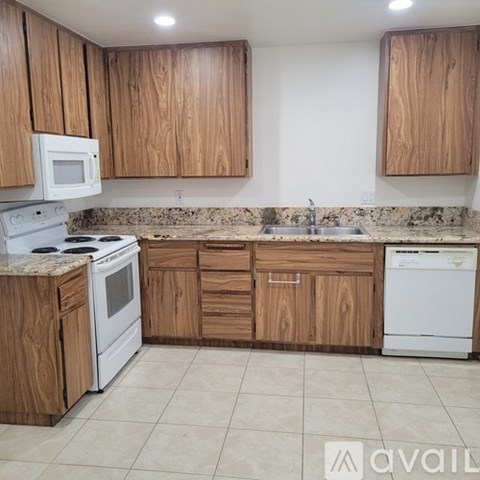 A kitchen with wooden cabinets and a white stove top oven.