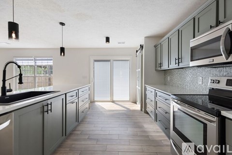 A kitchen with grey cabinets and black appliances.
