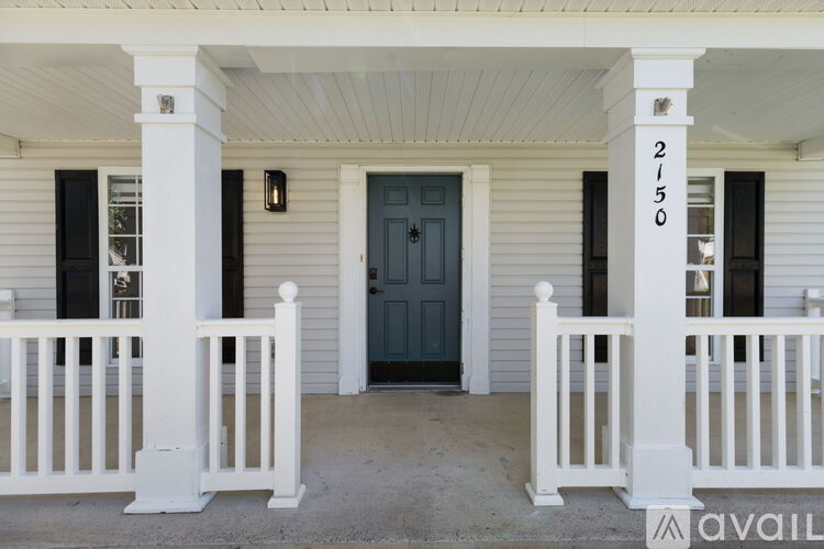 A white porch with a dark blue door and a white railing.