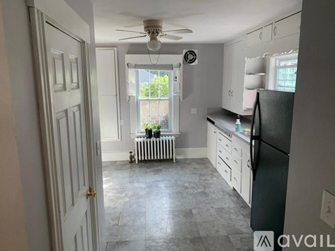 A kitchen with a black fridge and white cabinets.