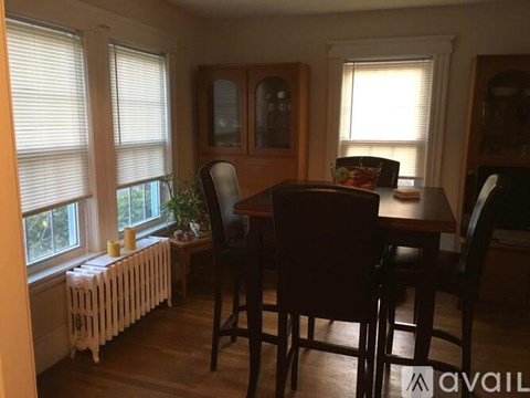 A dining room with a table, chairs, and a radiator.