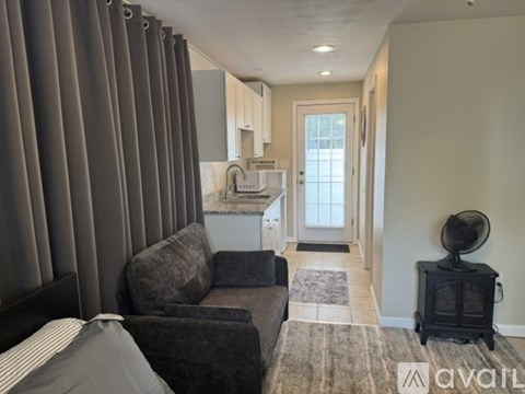 A living room with a grey couch and a black fan.