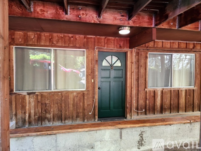 A wooden house with a green door and windows.