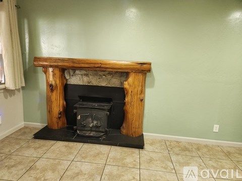 A wood fireplace with a black grate in the middle of a room with a green wall.