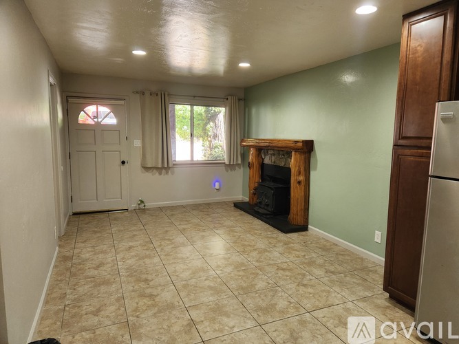 A living room with a fireplace and a refrigerator.