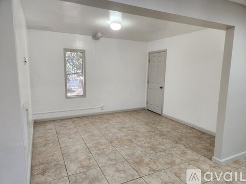 A room with a tiled floor and a window with a view of trees outside.