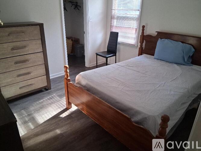 A bedroom with a bed, a chair, and a dresser.
