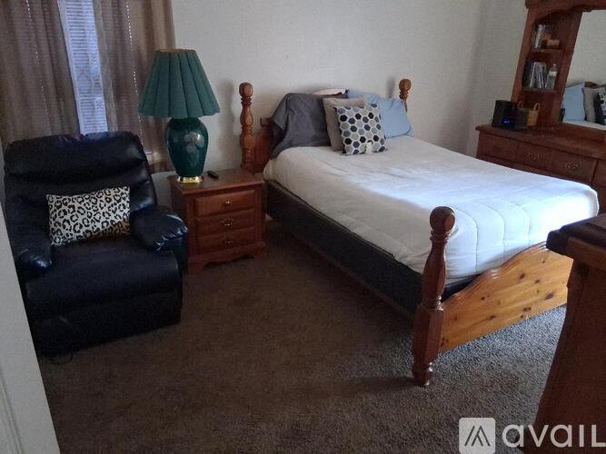 A bedroom with a bed, chair, and lamp.