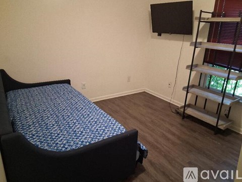 A bedroom with a bed, a TV, and a shelf.