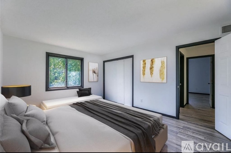 A bedroom with a large bed and a painting on the wall.