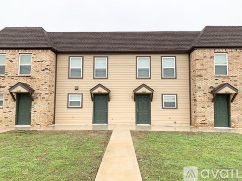 A brick house with a green door and a walkway in front.