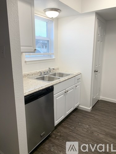 A kitchen with white cabinets and a stainless steel dishwasher.