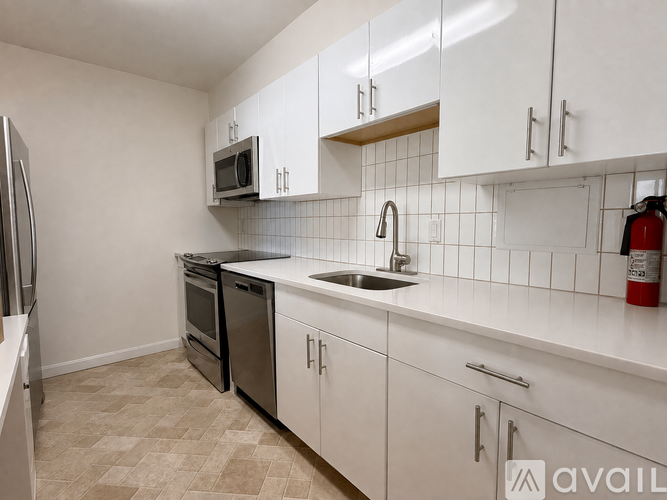 A kitchen with white cabinets and a black fridge.
