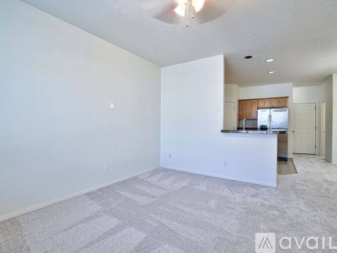 A spacious living room with a carpeted floor and a ceiling fan.