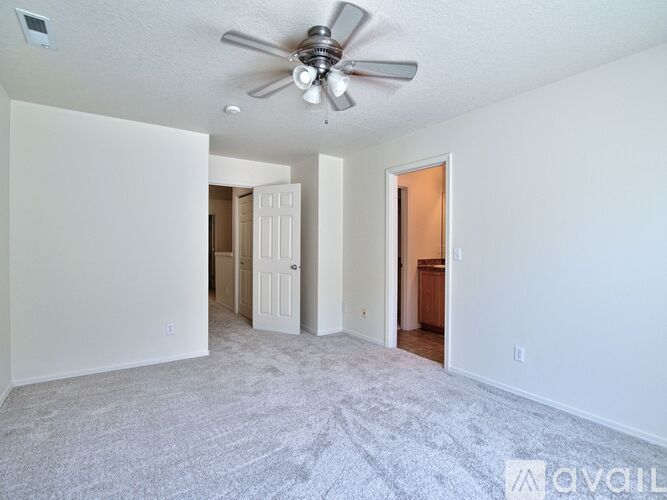 A spacious room with a ceiling fan and carpeted floor.