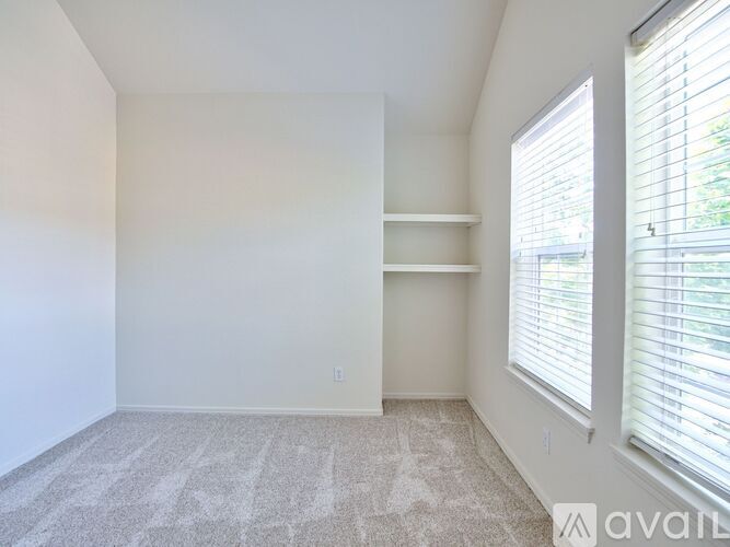 A room with a carpeted floor and a window with blinds.