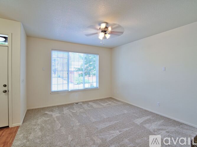 A room with a carpeted floor and a ceiling fan.