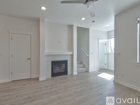 A spacious living room with a fireplace and a staircase.