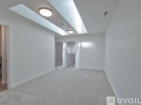 A spacious, empty room with a carpeted floor and white walls.