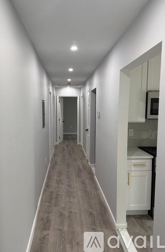 A long hallway with white walls and wood flooring.