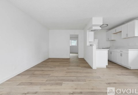 A kitchen with white cabinets and a wooden floor.